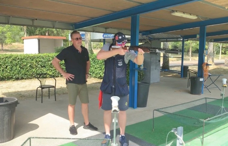 man pointing gun while being watched behind